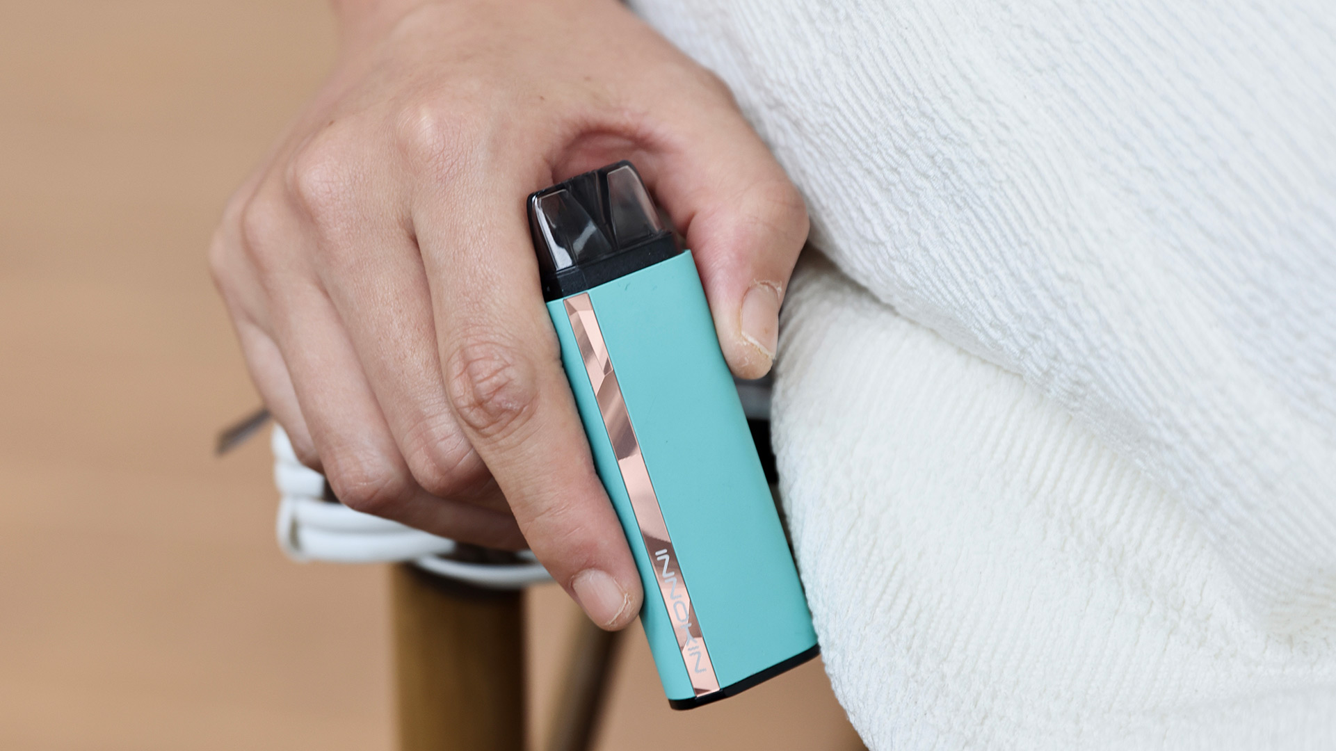 Persona che tiene in mano una pod sigaretta elettronica preriempita Innokin Klypse di colore turchese.