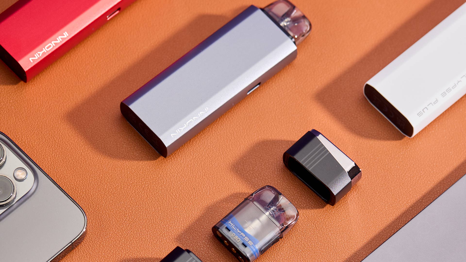 pod mod Innokin Klypse  pod mod vari colori esposto su una superficie arancione testurizzata.